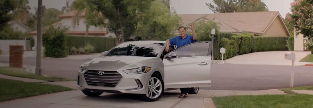 A man stands next to a silver Hyundai car