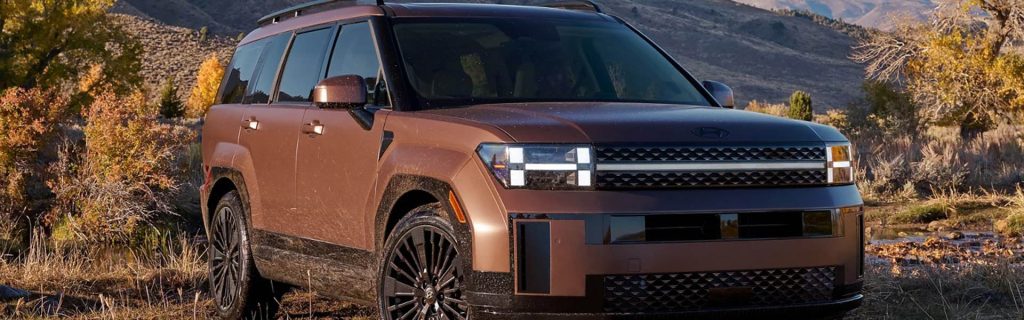 Bronze Hyundai SUV driving through rugged terrain with a mountainous backdrop.